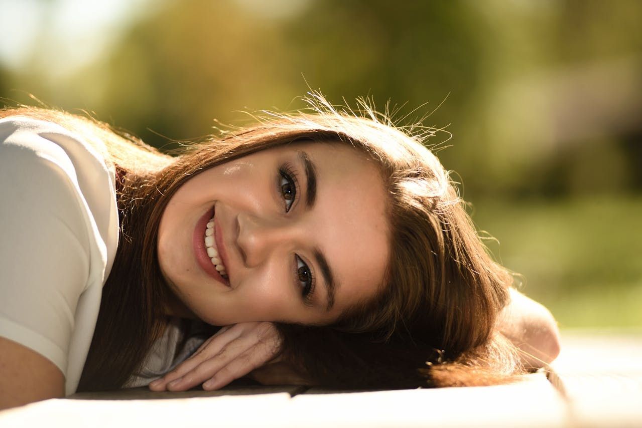 A woman is laying on her stomach on the ground and smiling.
