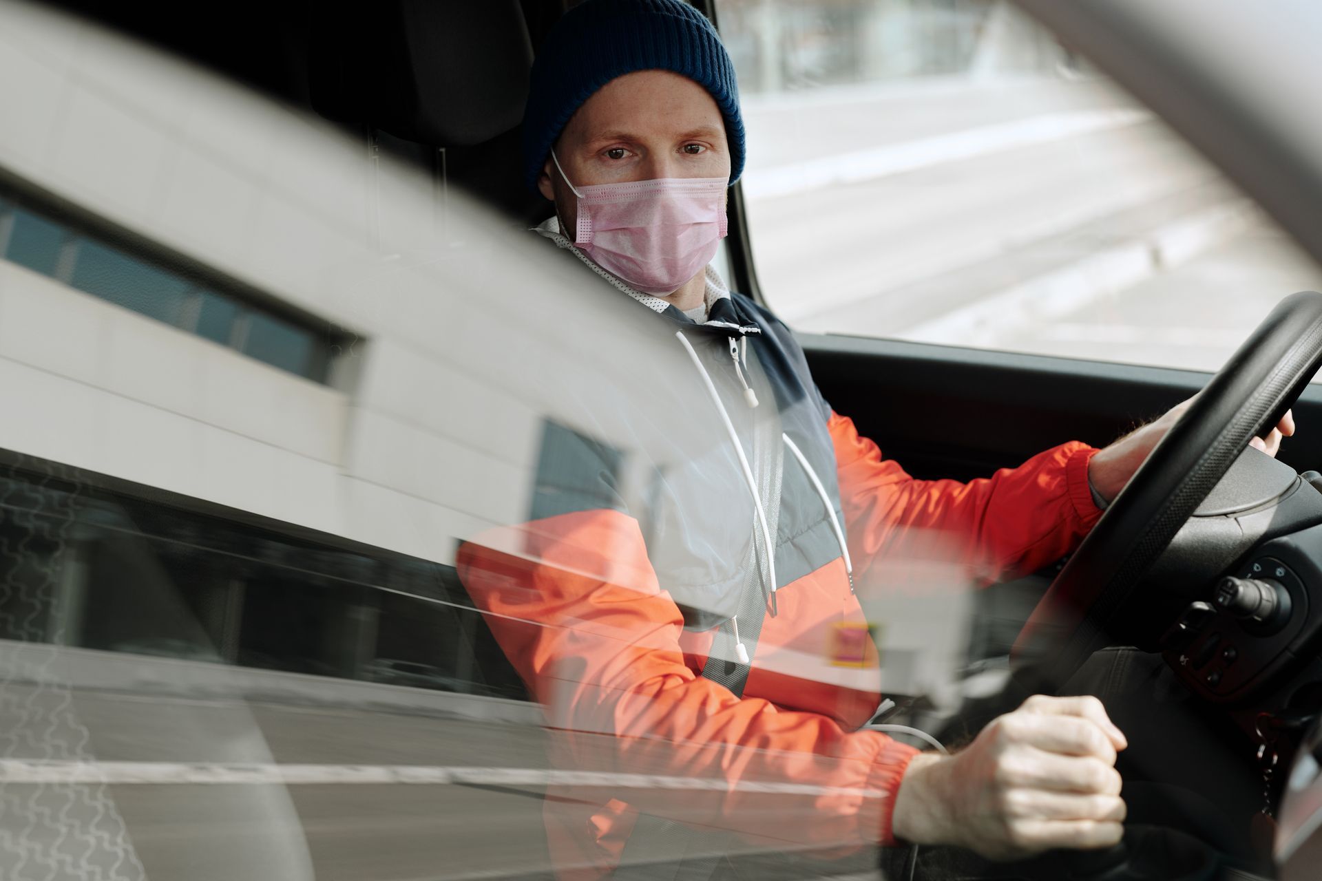 A man wearing a face mask is driving a car.