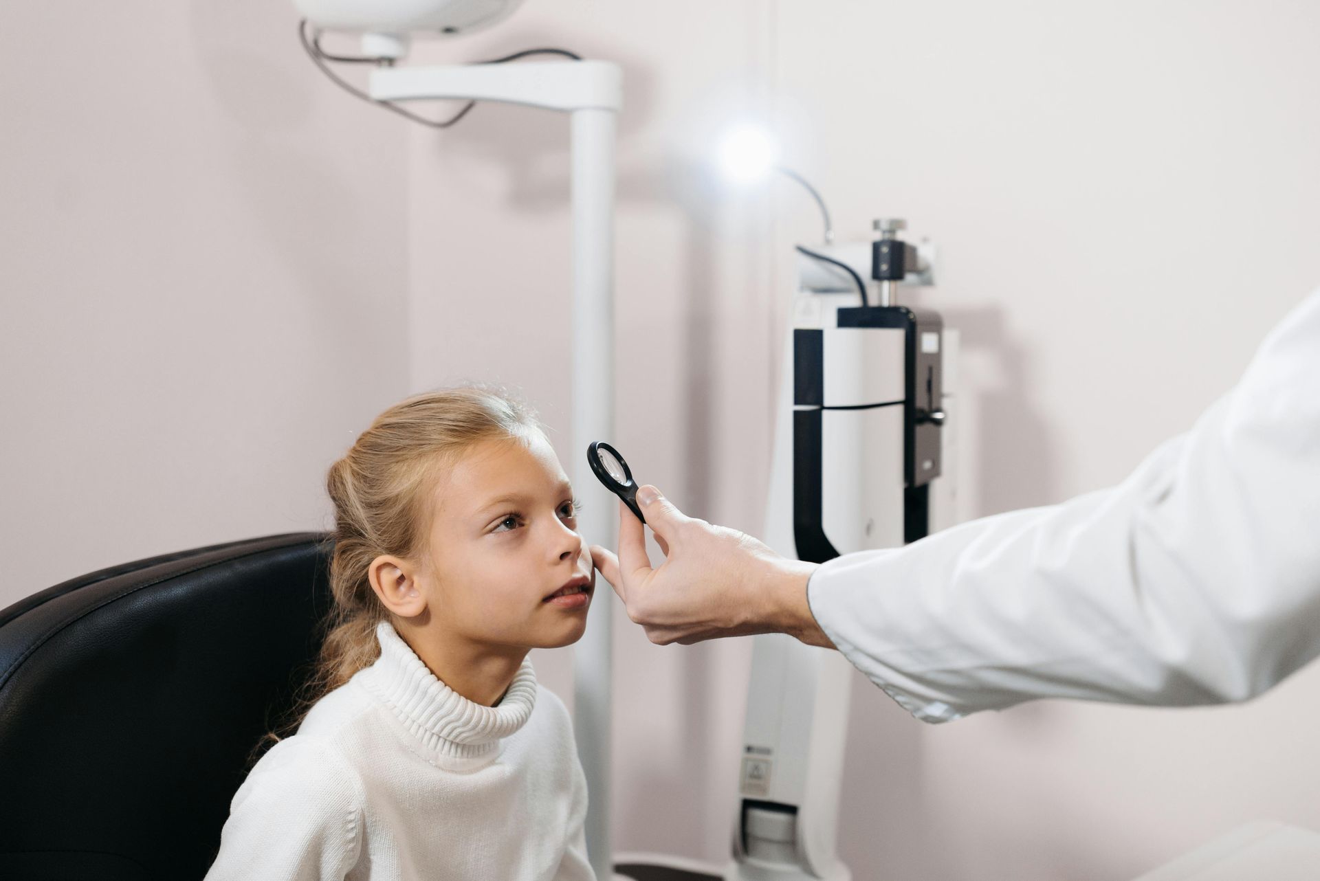 A little girl is having her eyes examined by an optometrist.
