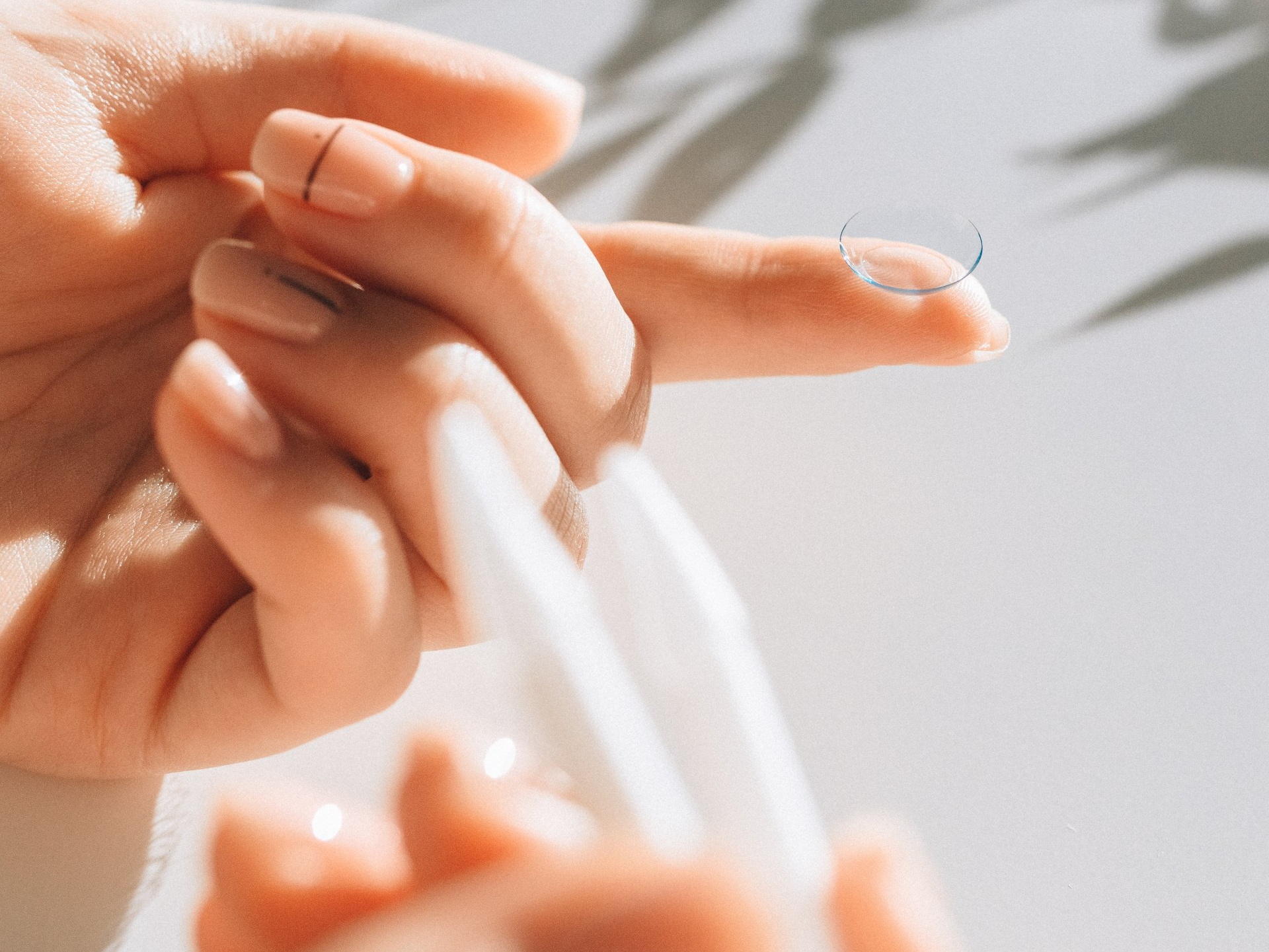 A person is putting a contact lens on their finger.