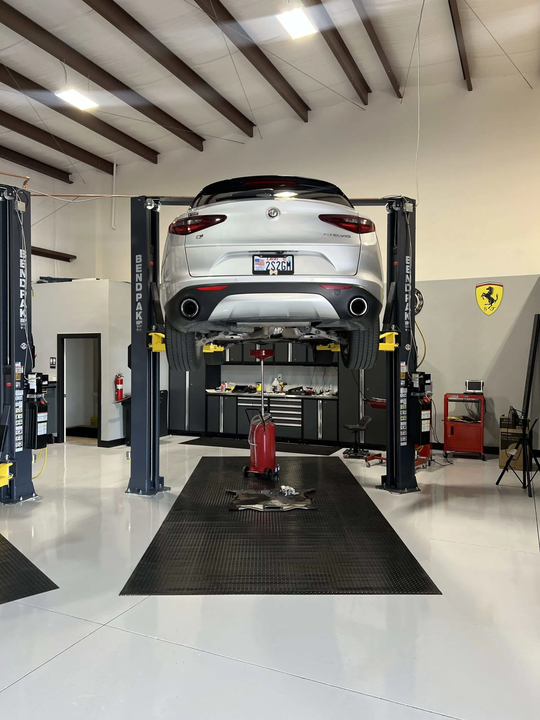 Silver sports car on a lift in a clean auto garage, with tools and equipment around it