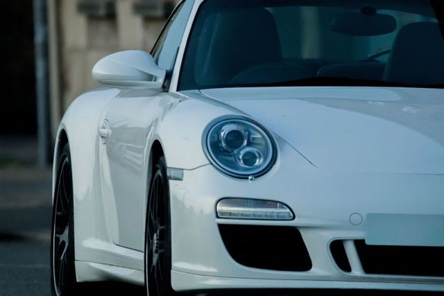 White sports car parked outdoors, close-up front view with a city background
