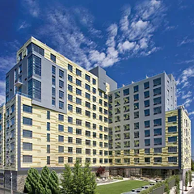 Modern beige and blue multi-story hotel building under a bright blue sky