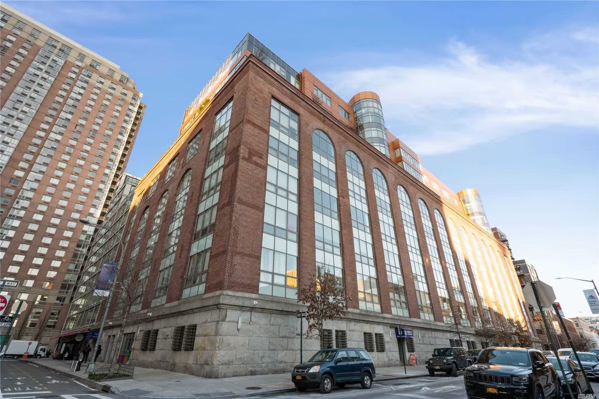 Brick building with tall windows on a snowy city street, viewed from a low angle at sunset.