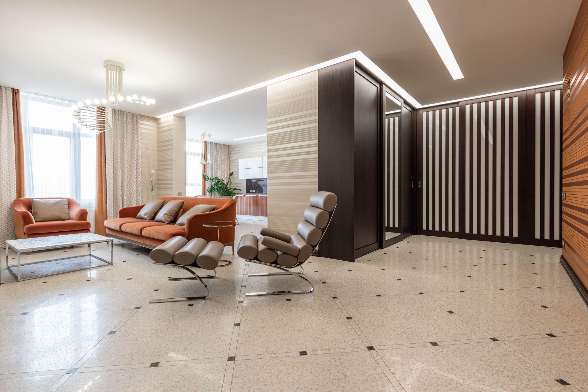 Modern lounge with orange sofas, recliner chairs, striped wall, and bright marble floor.