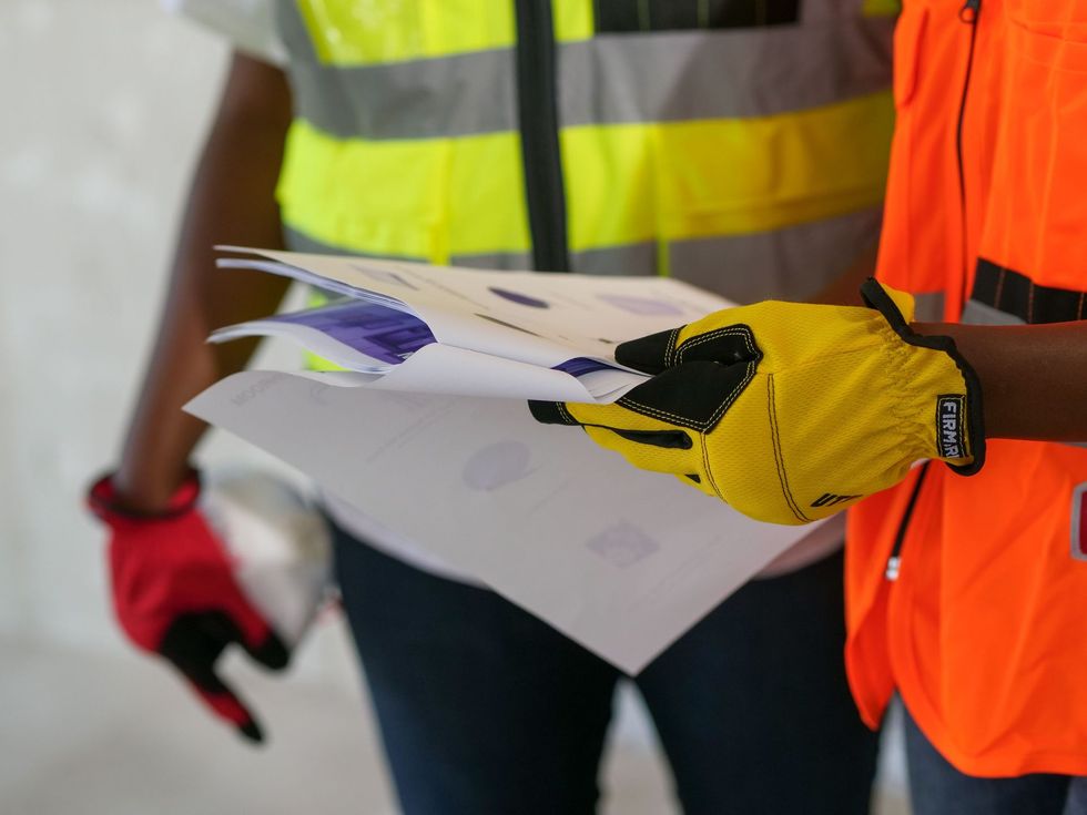 Workers in high-visibility vests reviewing plans on a construction site