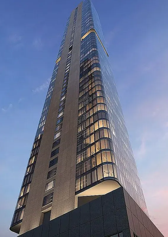 Tall modern skyscraper with a curved glass facade against a blue evening sky