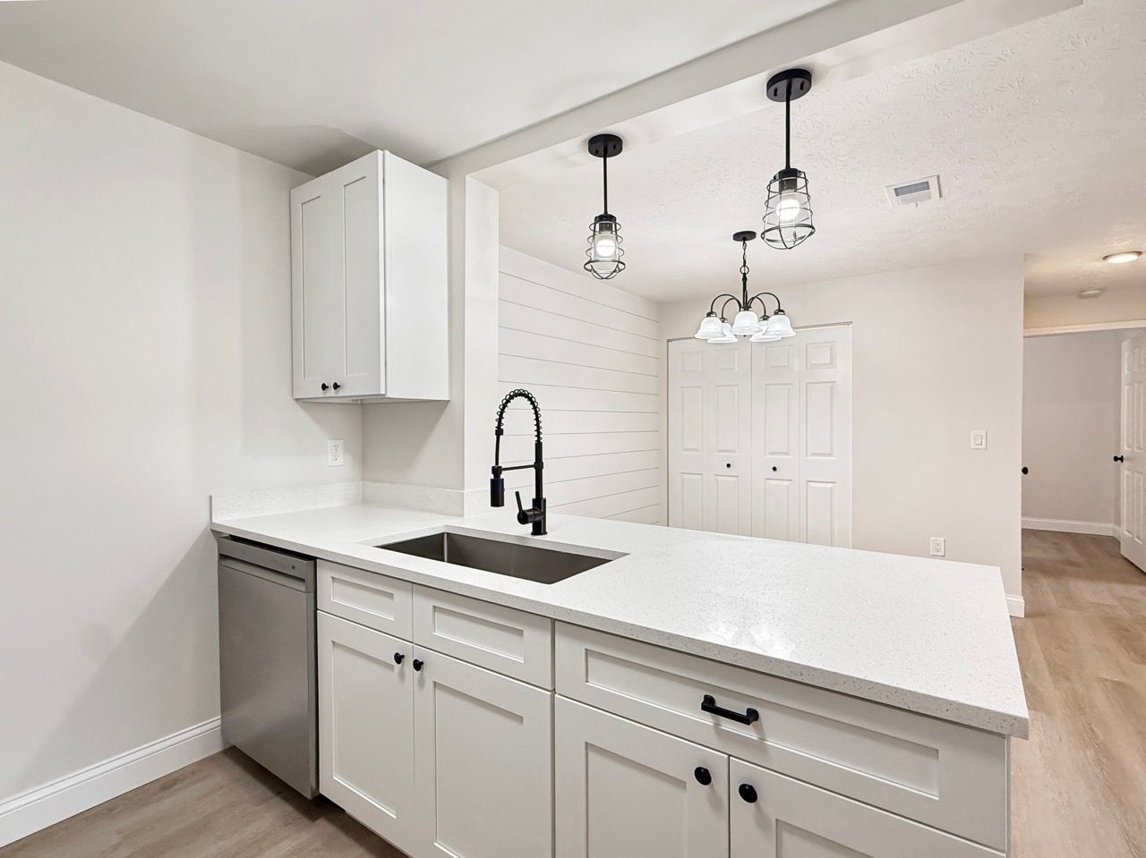 Bright modern kitchen with white cabinets, quartz island, black faucet, and pendant lights