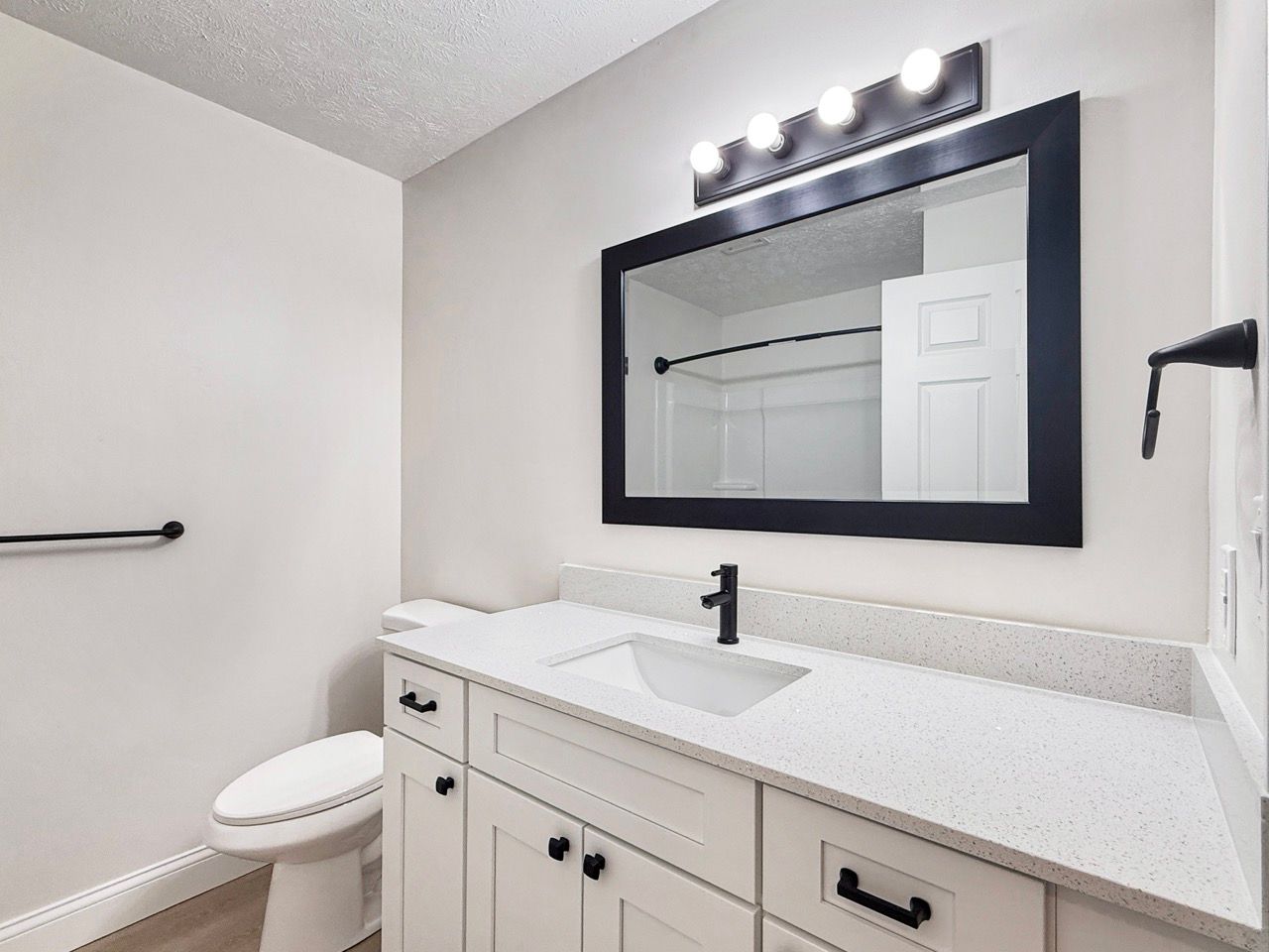 Bright bathroom vanity with mirror, white countertop, and black fixtures