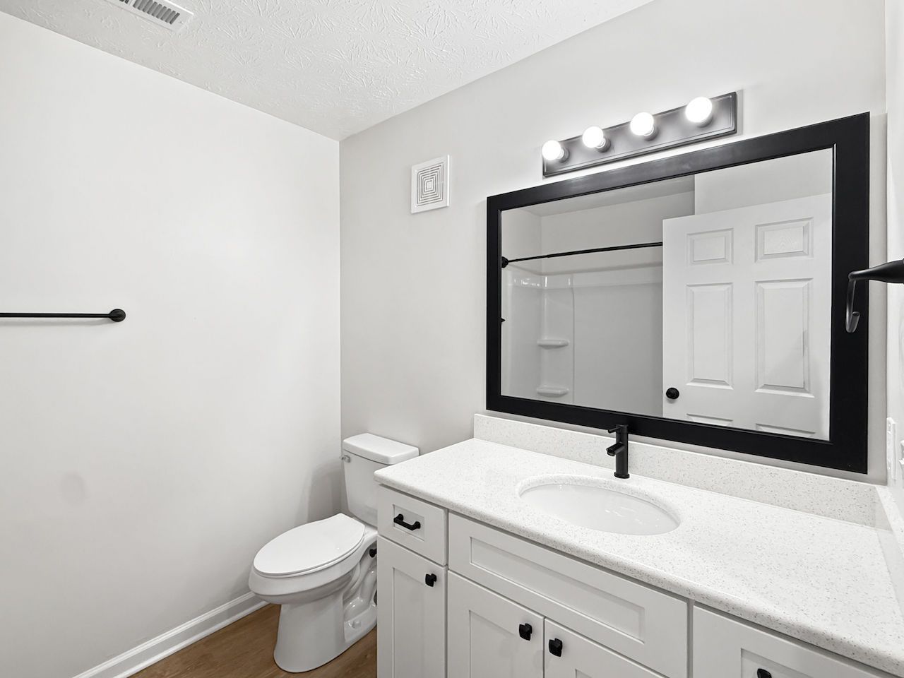 Modern bathroom with white vanity, toilet, and large mirror with lights