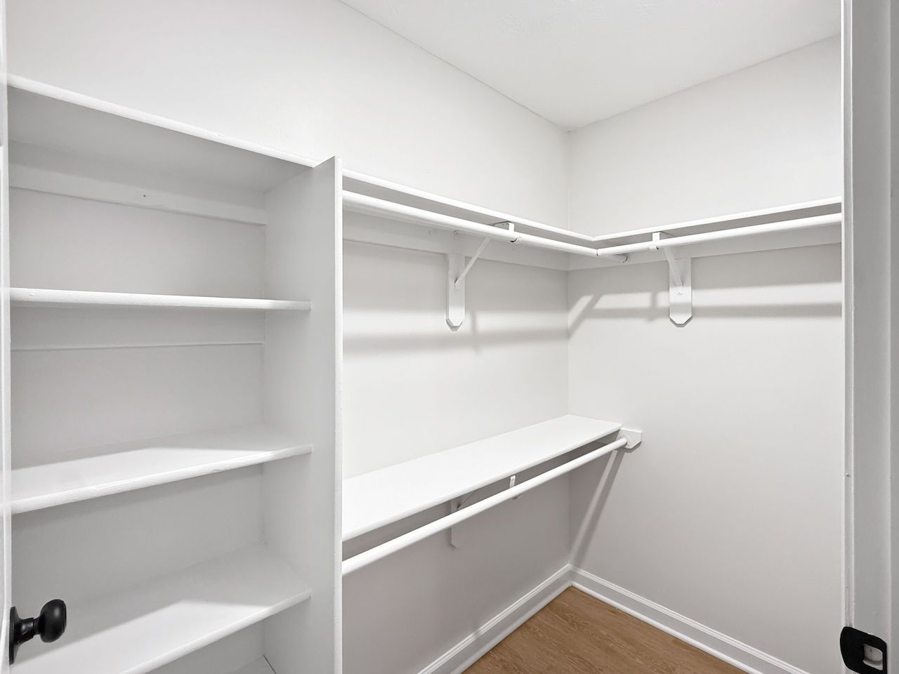 Empty white walk-in closet with shelves and hanging rods