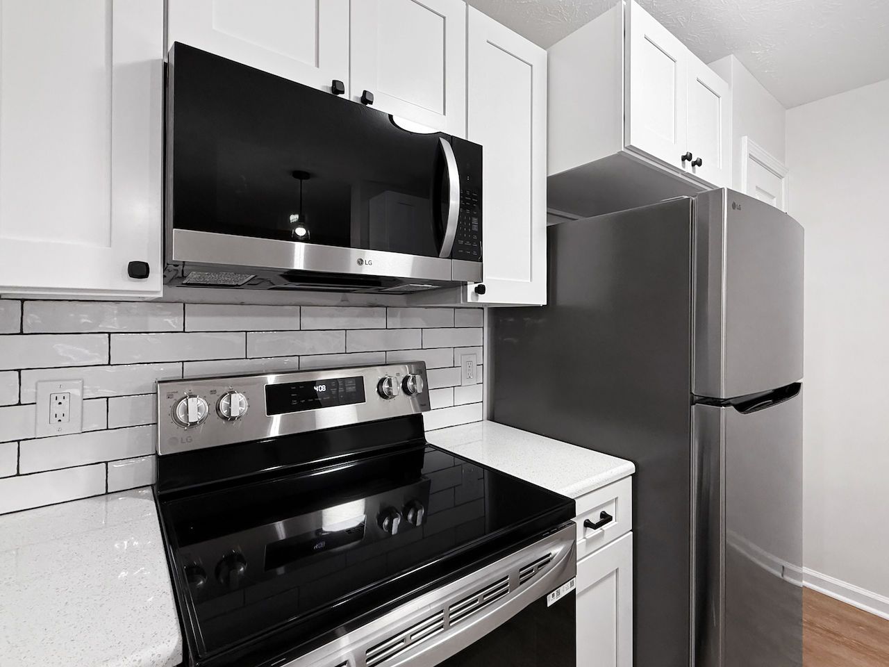 Modern kitchen with black appliances, white cabinets, and a stainless steel refrigerator.