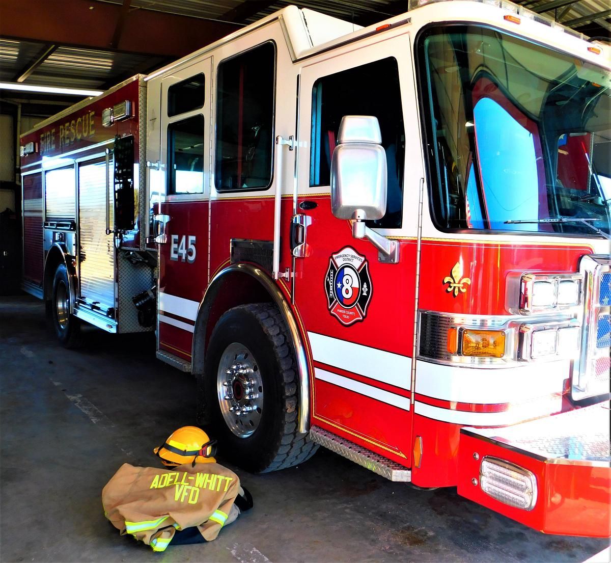 Red fire truck parked in a station bay, with equipment compartments open.