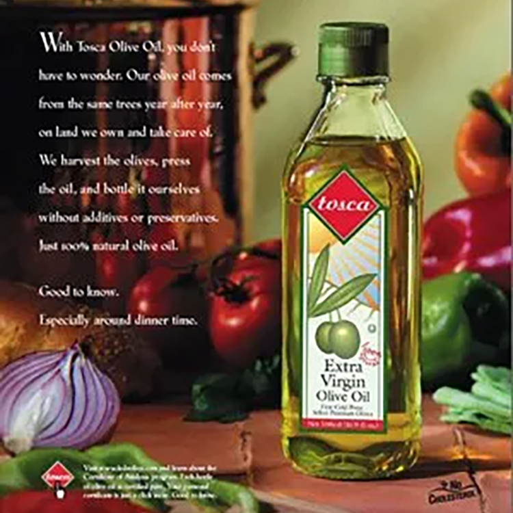 Bottle of Tosca Extra Virgin Olive Oil with vegetables in the background, promoting the olive oil.