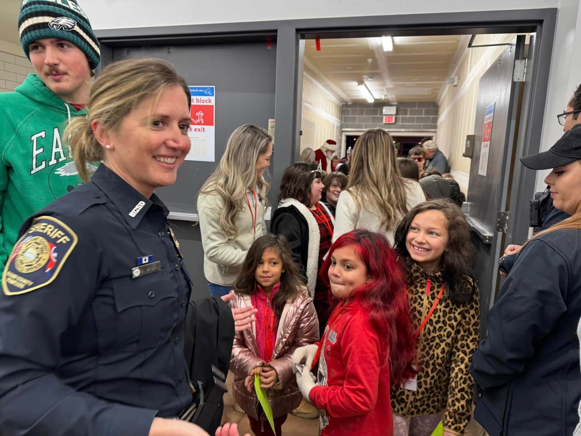 A police officer is standing in a hallway with a group of children.