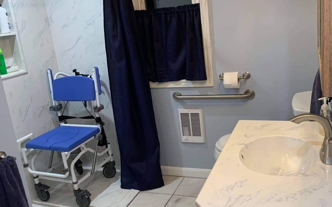 Bathroom with a blue shower chair, dark blue shower curtain, and a countertop sink.