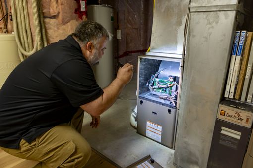 licensed house inspector in yellow safety vest near baseboard near a wall outlet in a room