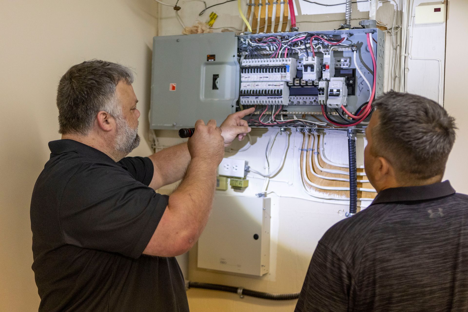 Two home inspectors examining a circuit board