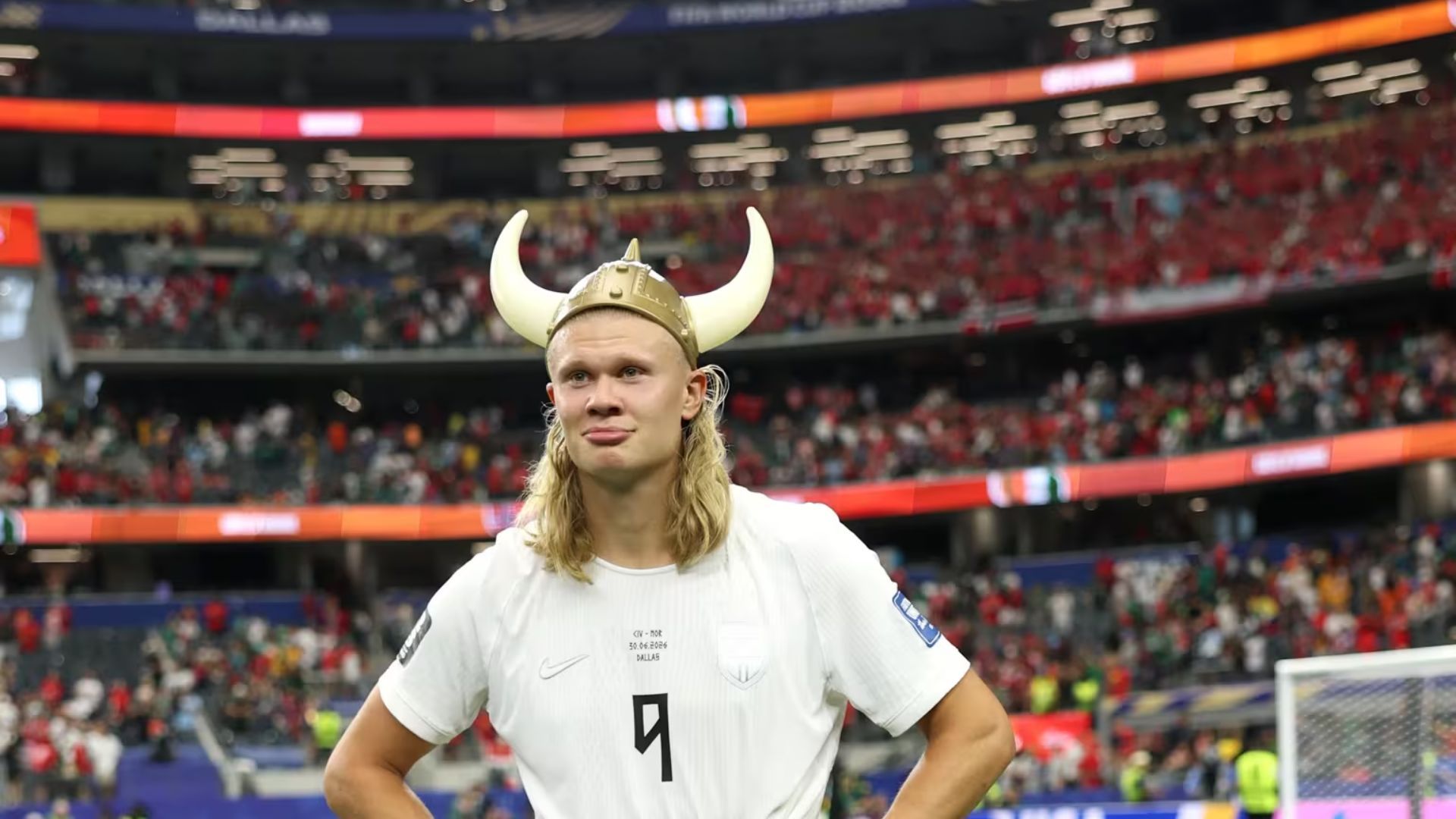 Soccer player in white jersey wearing a Viking helmet, standing on the field in a stadium