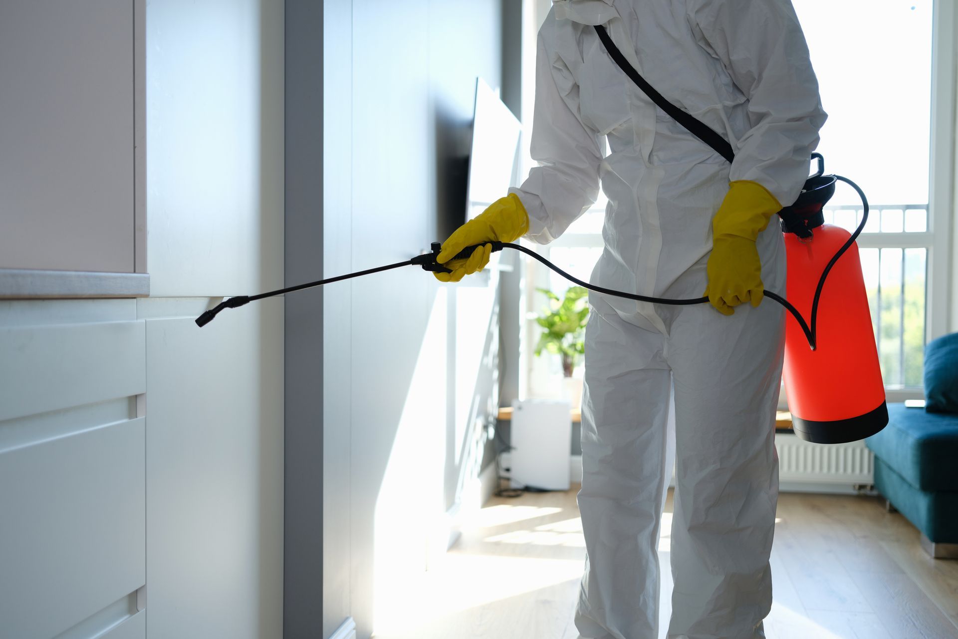 An exterminator, wearing protective overalls and gloves, performing local pest control services.
