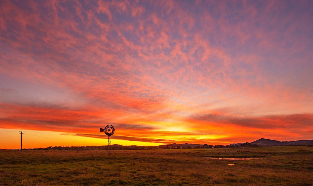 A Windmill In The Middle Of A Field At Sunset — Tim's Towing and Transport In East Maitland, NSW