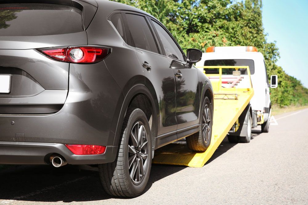 A Car Is Being Towed By A Tow Truck — Tim's Towing and Transport In Branxton, NSW