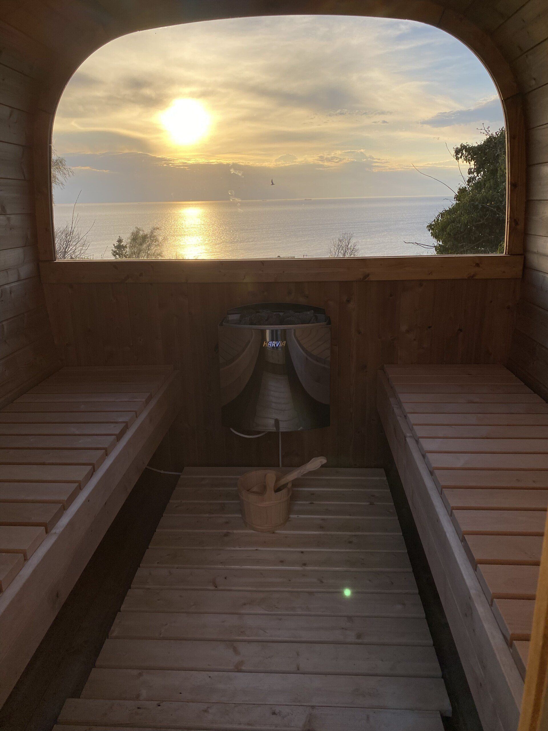 Træsauna interiør med udsigt over en solnedgang over roligt vand