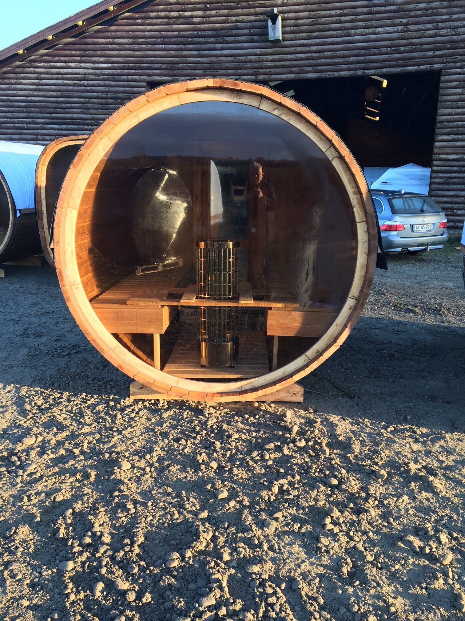 Rund træsaunakapsel udendørs med glasfront og synlig bænk indeni