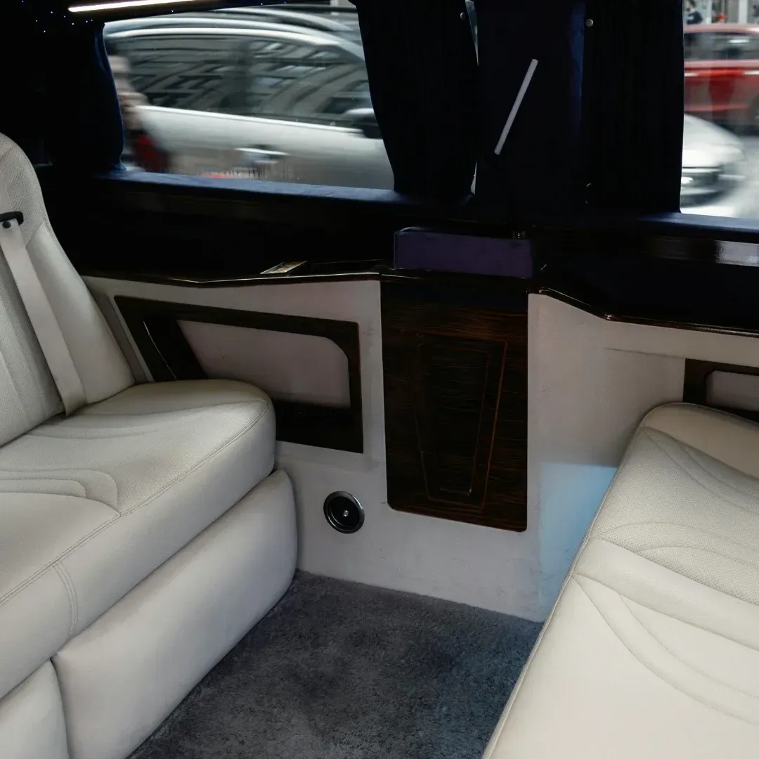 Luxury car interior with white leather seats, gray carpet, and dark wood trim by the window Luxury car interior with white leather seats, gray carpet, and dark wood trim by the window