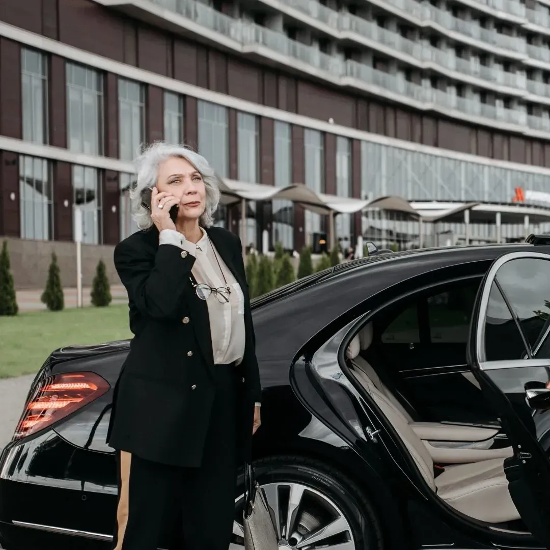 Business executive standing beside a luxury chauffeured car during an hourly executive car service i
