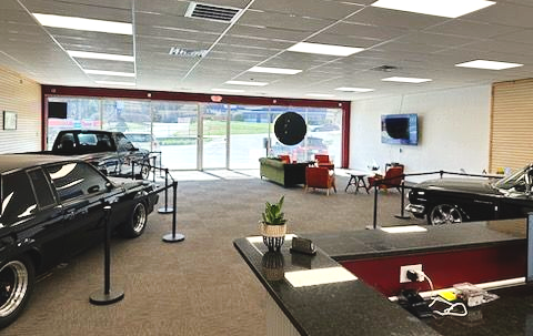 A black, two-story commercial building with an auto service shop on the ground floor and a parking lot in front.