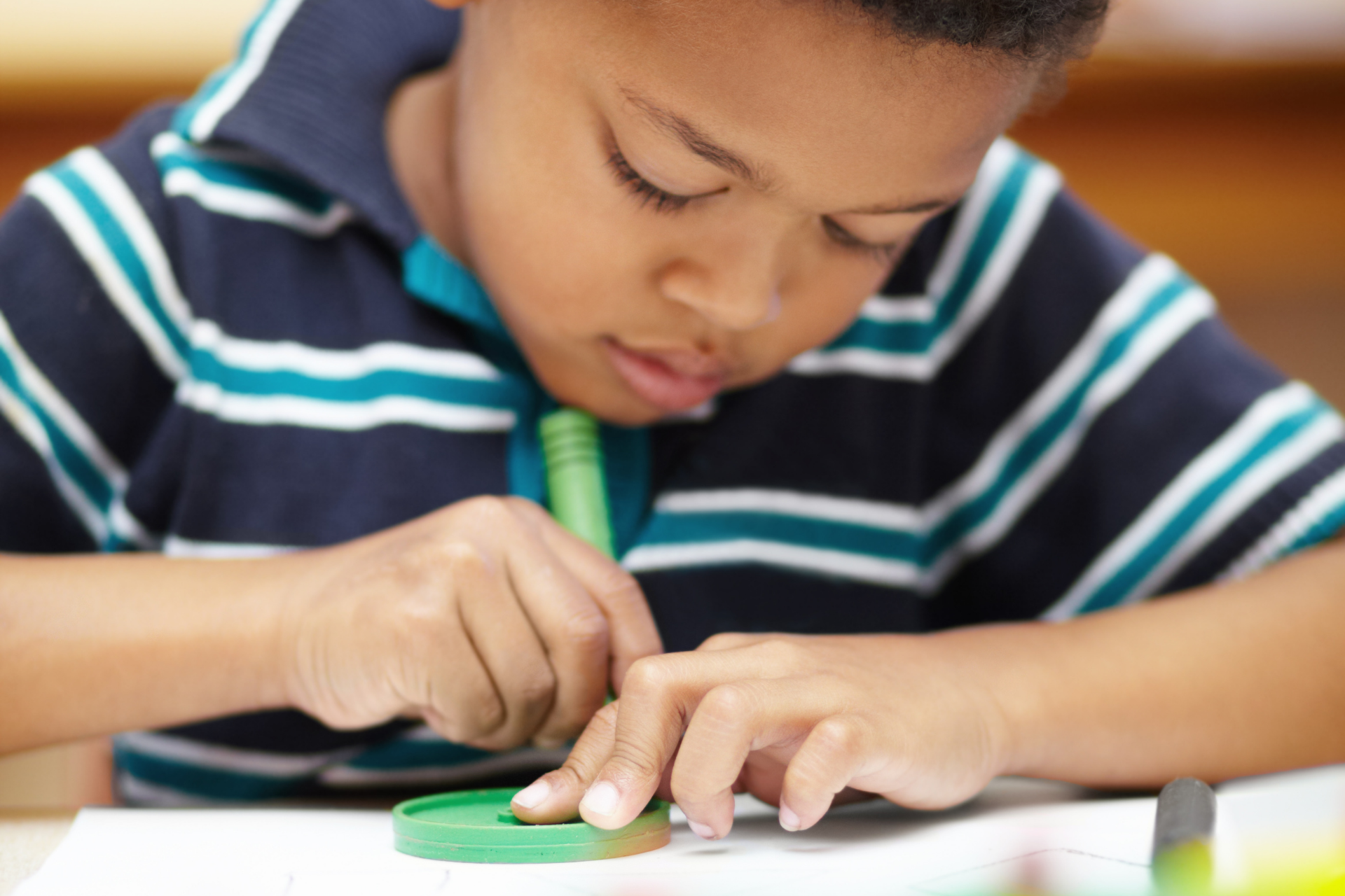Boy concentrating while using a magnifying glass on a table