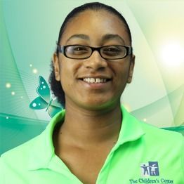 Smiling person in glasses wearing a bright green shirt against a soft green backdrop with butterfly graphic