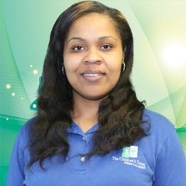 Woman in a blue polo shirt smiling against a soft green abstract background.