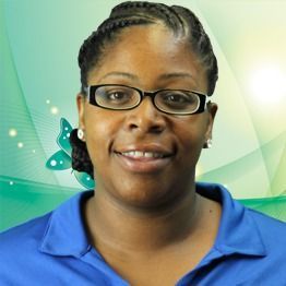Smiling person in glasses wearing a blue polo against a green abstract background.