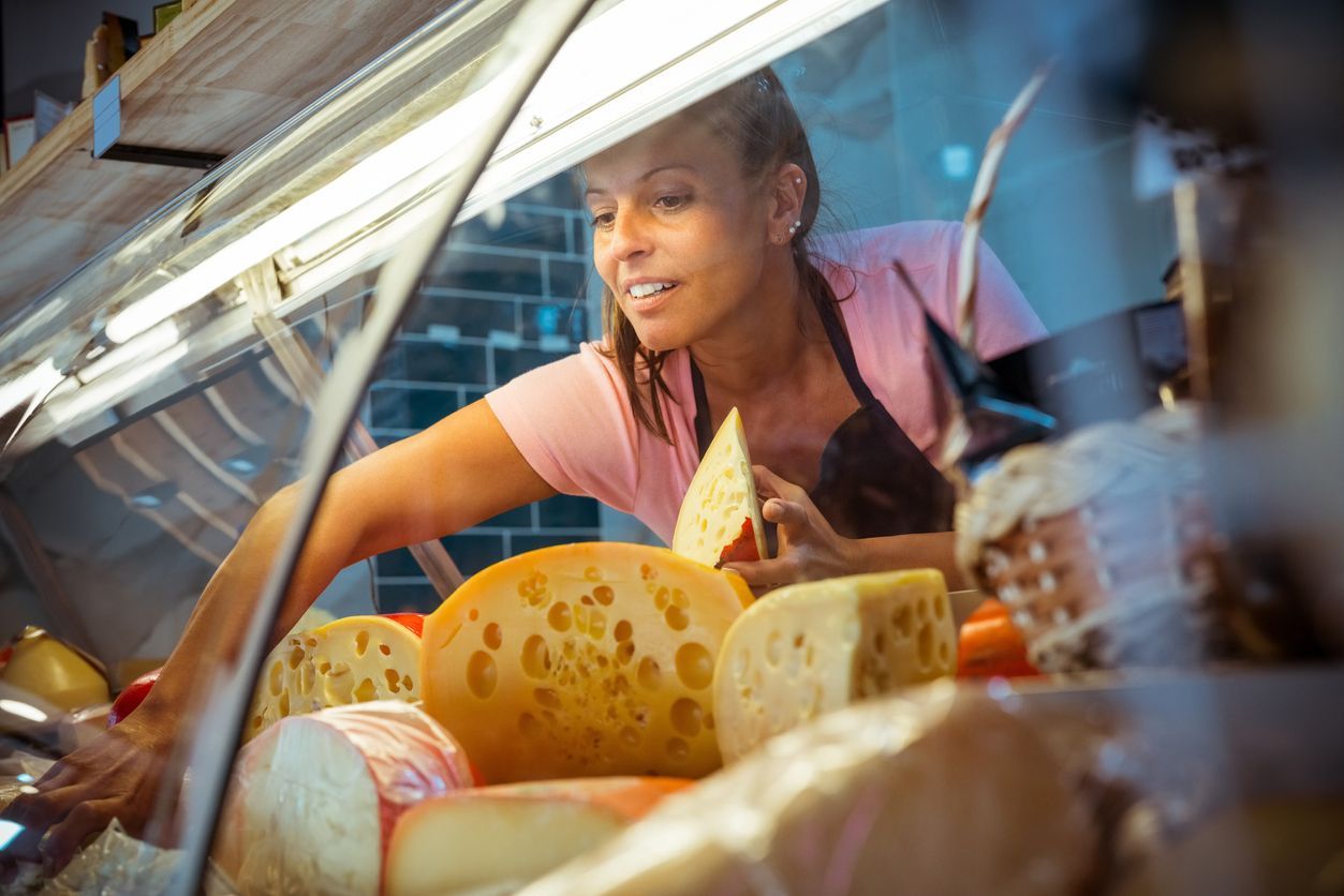woman taking cheese out of commercial refrigerator in Philadelphia, PA