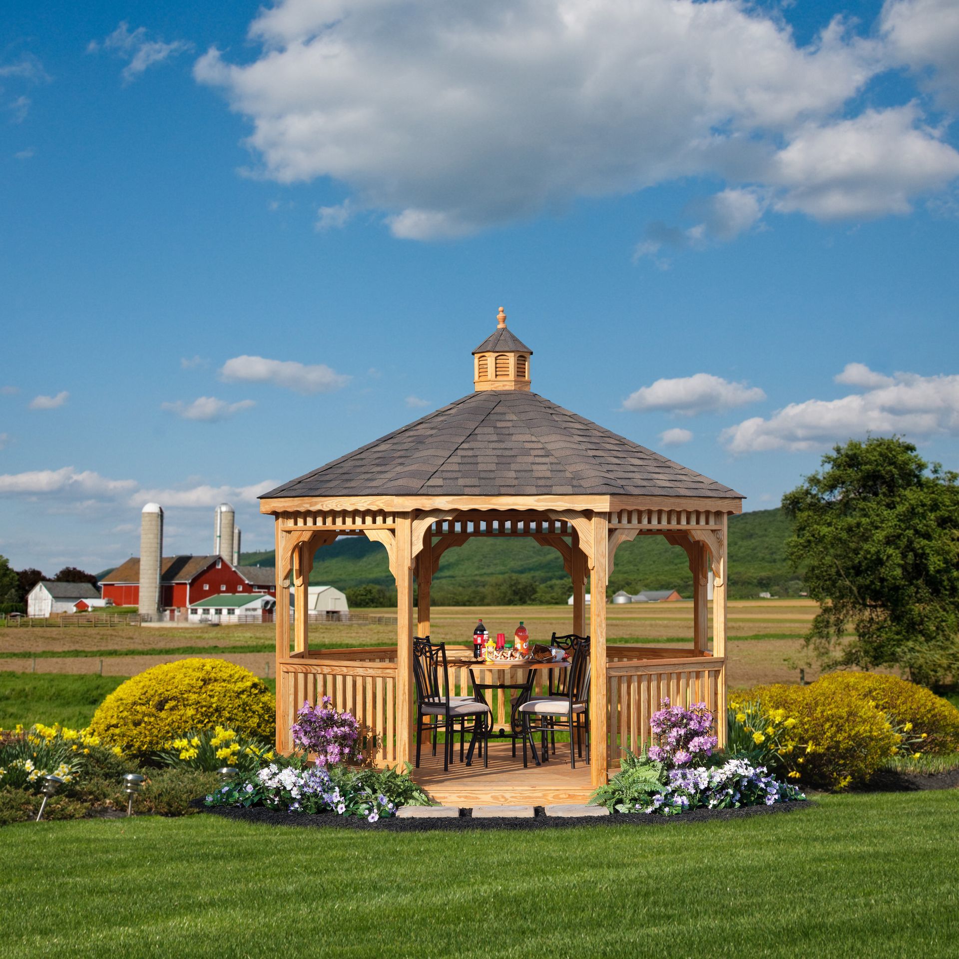 a gazebo with a table and chairs in the middle of a grassy field