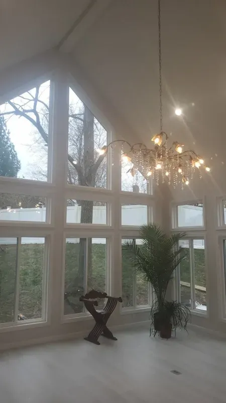 Bright room with tall windows, chandelier, and a palm plant on a light floor