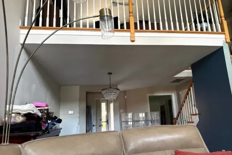 Living room with beige sofa, staircase, balcony railing, and hanging light fixture