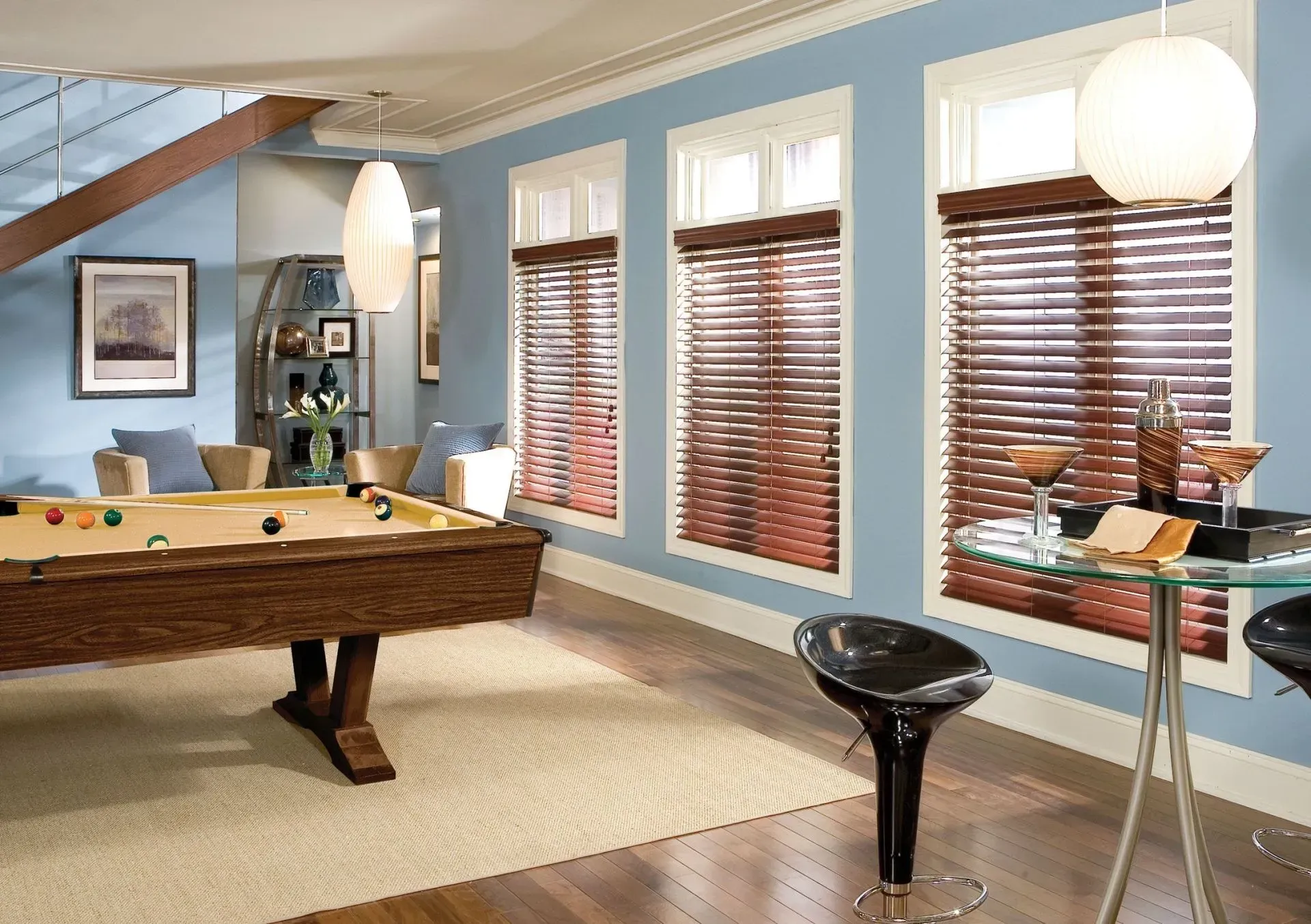 Spacious game room with pool table, pendant lights, windows with blinds, and a glass side table