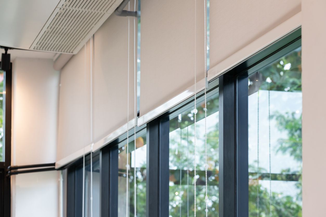 Modern office interior with tall windows, beige blinds, and daylight outside