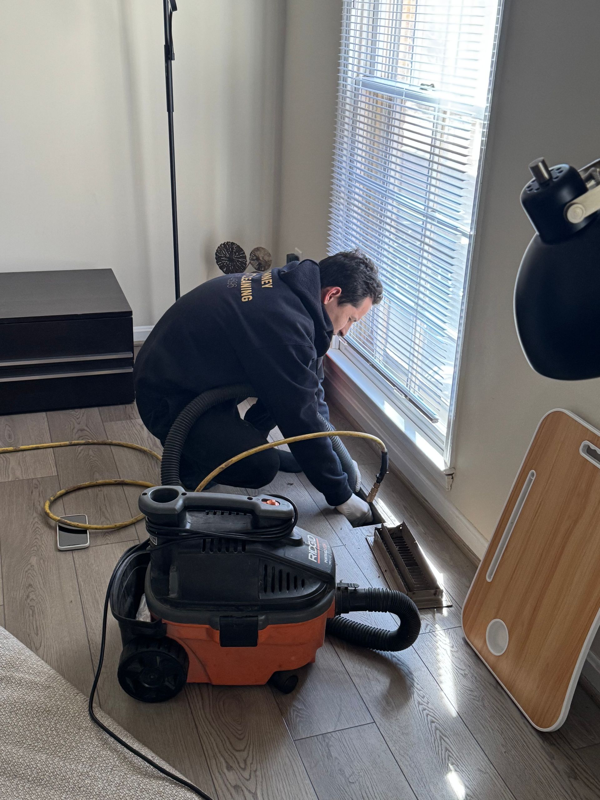 A man is cleaning the floor with a vacuum cleaner.