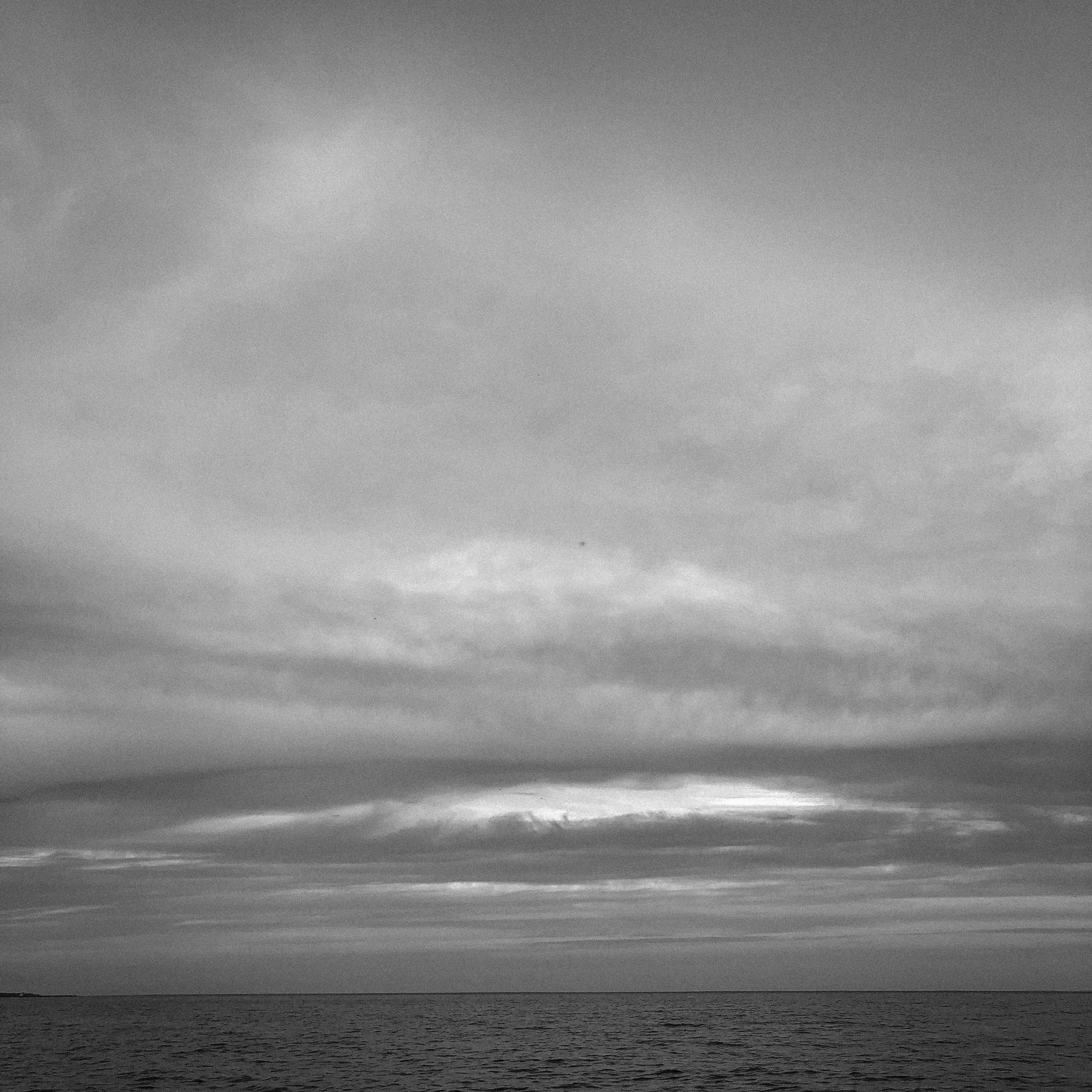 Ocean scene with cloudy sky in grayscale.