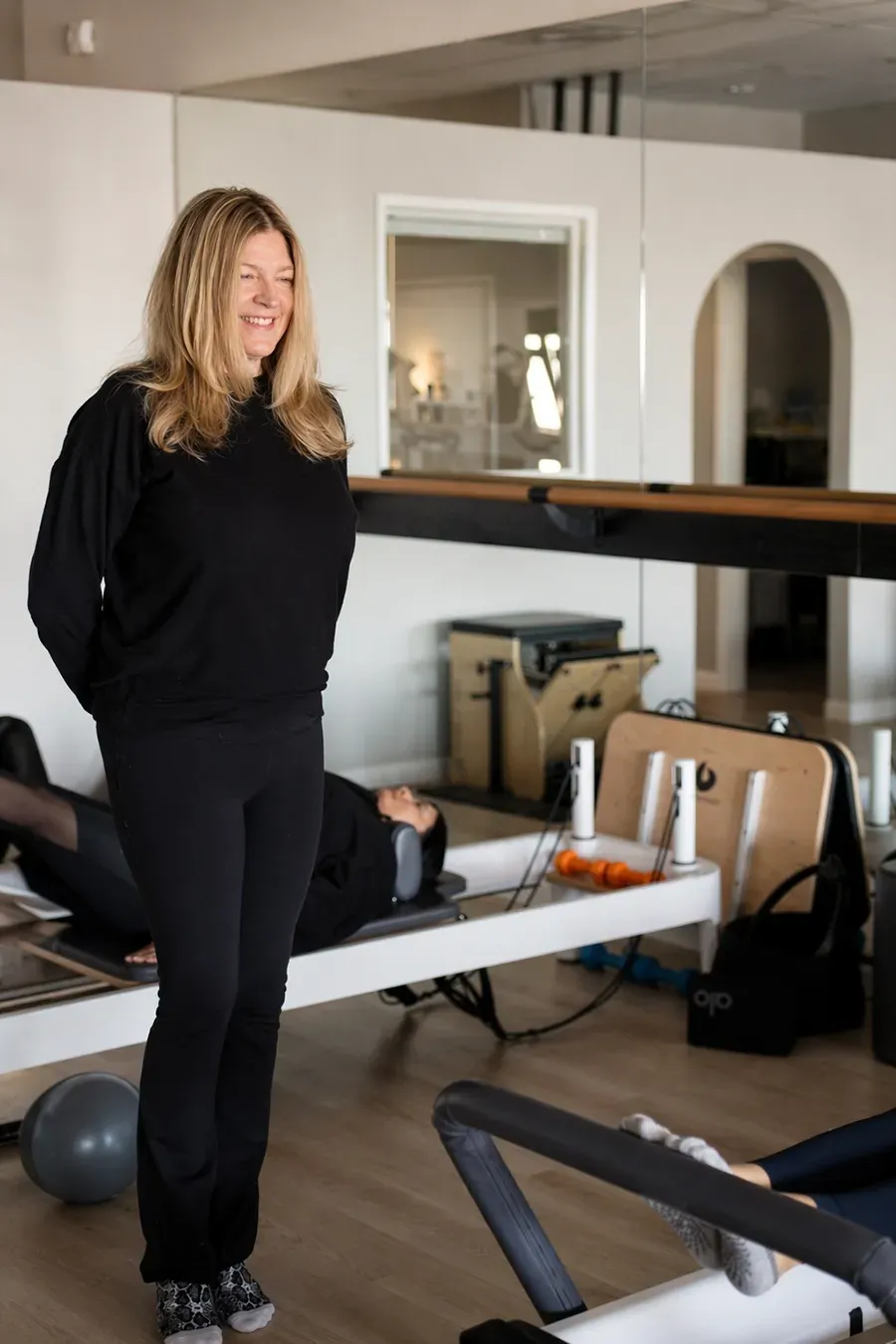 Woman standing in a studio with exercise equipment and mirrors behind her