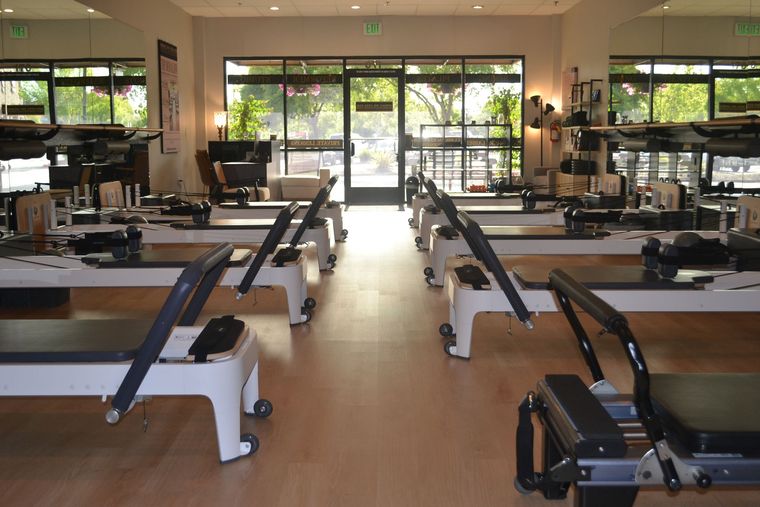 Modern Pilates studio with reformer machines lined up in a bright room