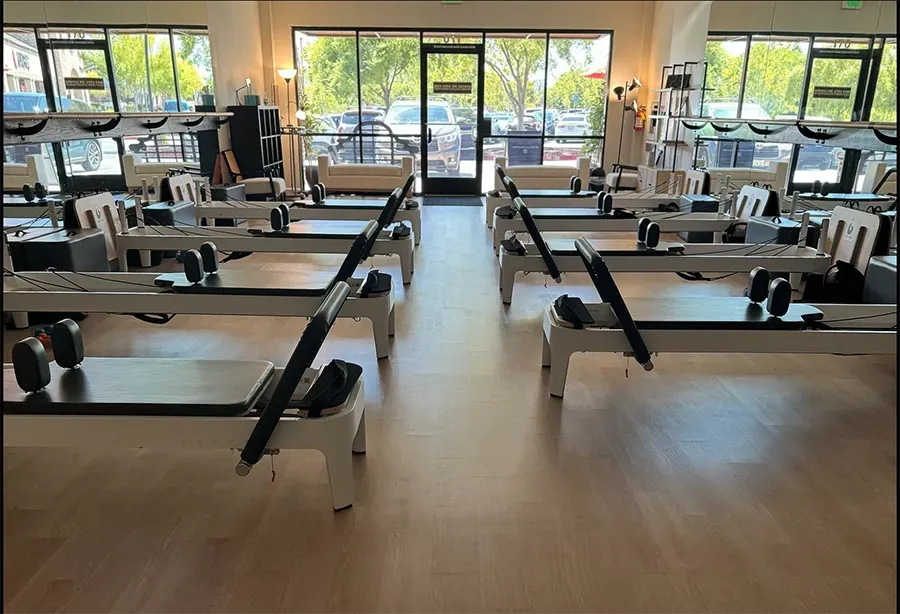Empty Pilates studio with reformer machines and large windows