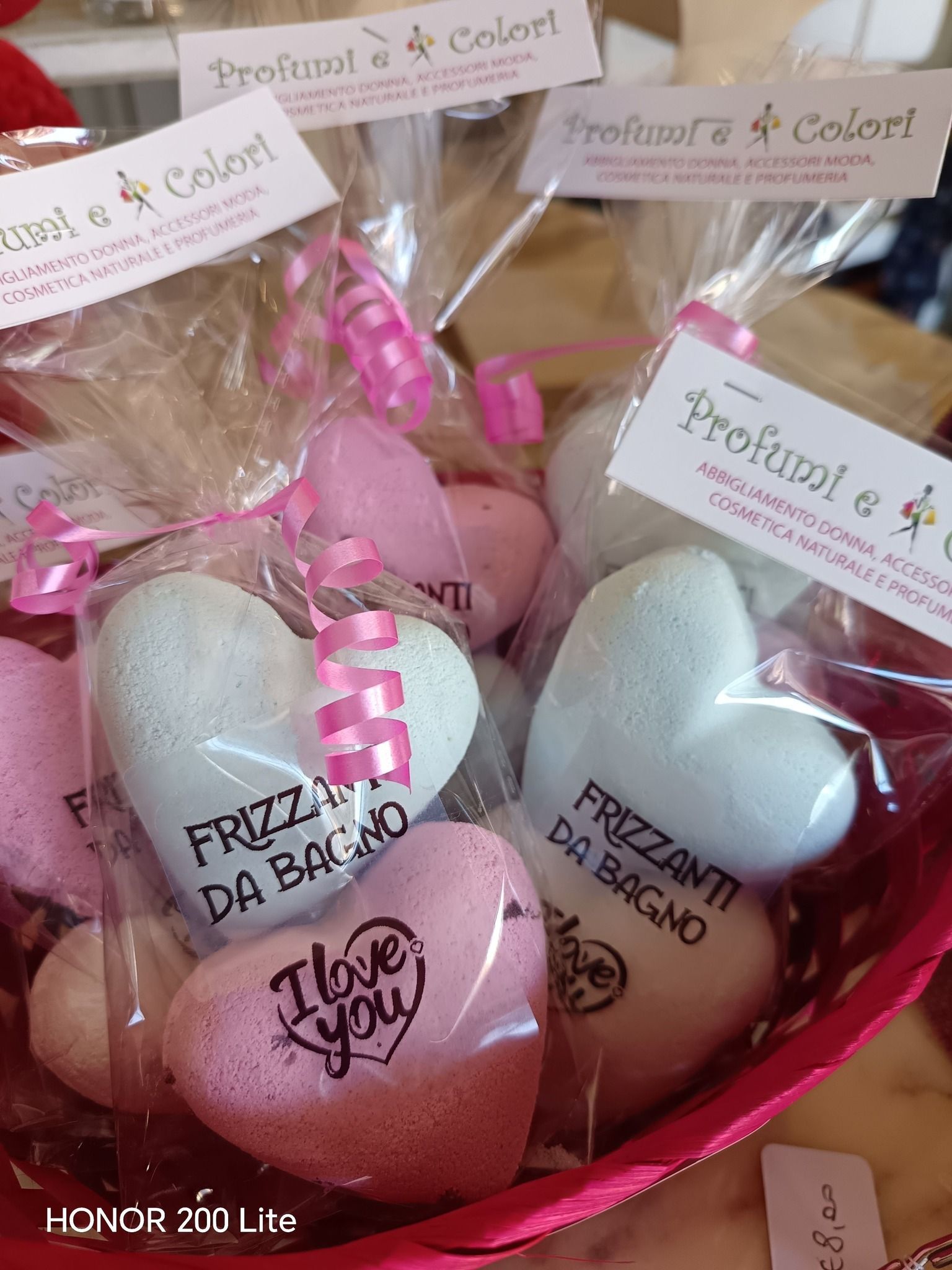 Bombe da bagno a forma di cuore in un cestino, avvolte nel cellophane e legate con nastri rosa. Alcune dicono