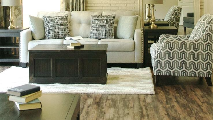 A living room with a couch , chair , coffee table and rug.
