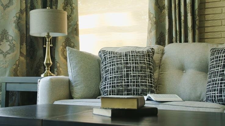 A living room with a couch , table , lamp and a book on the table.
