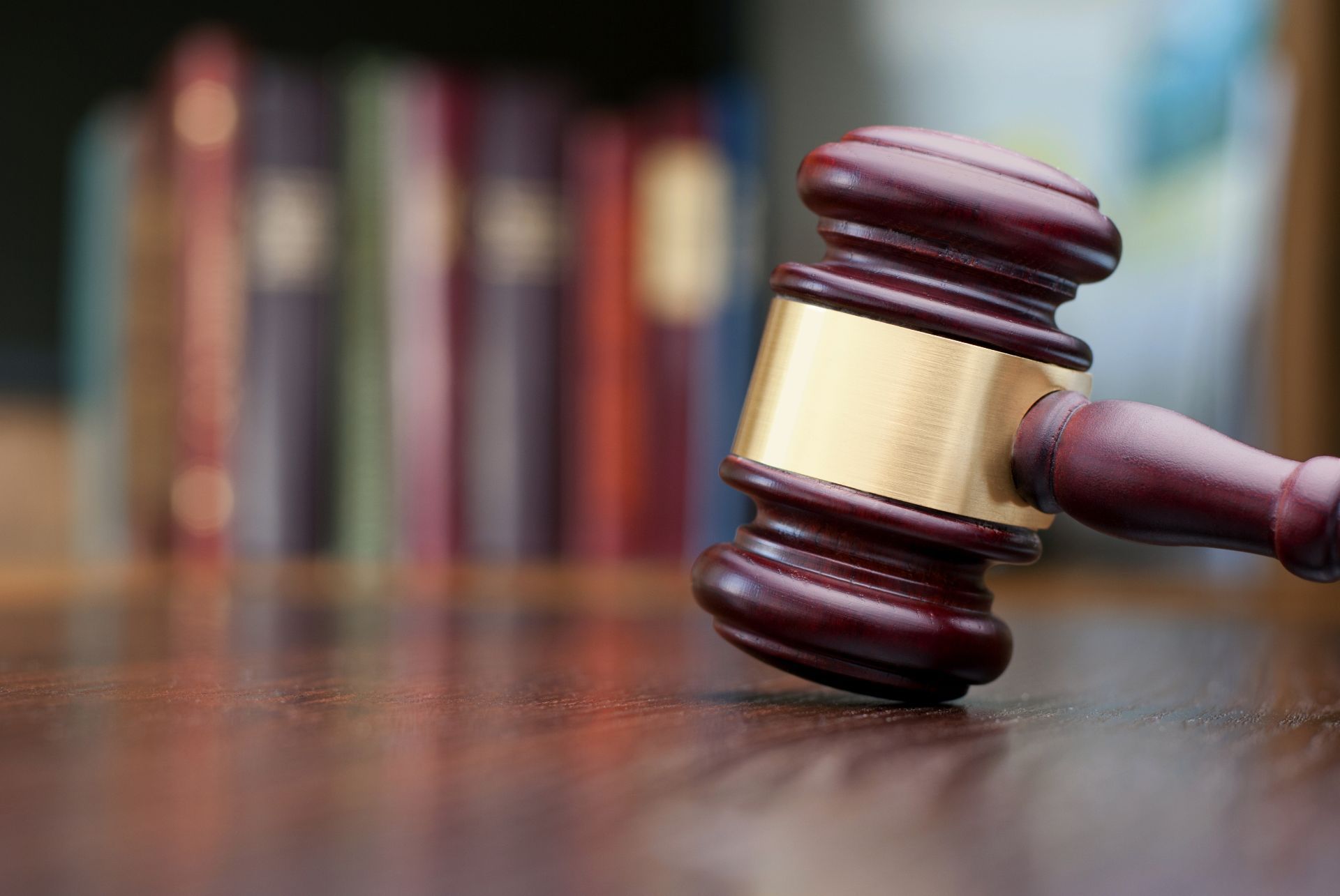 Judge’s gavel with gold band resting on a wooden surface in a courtroom